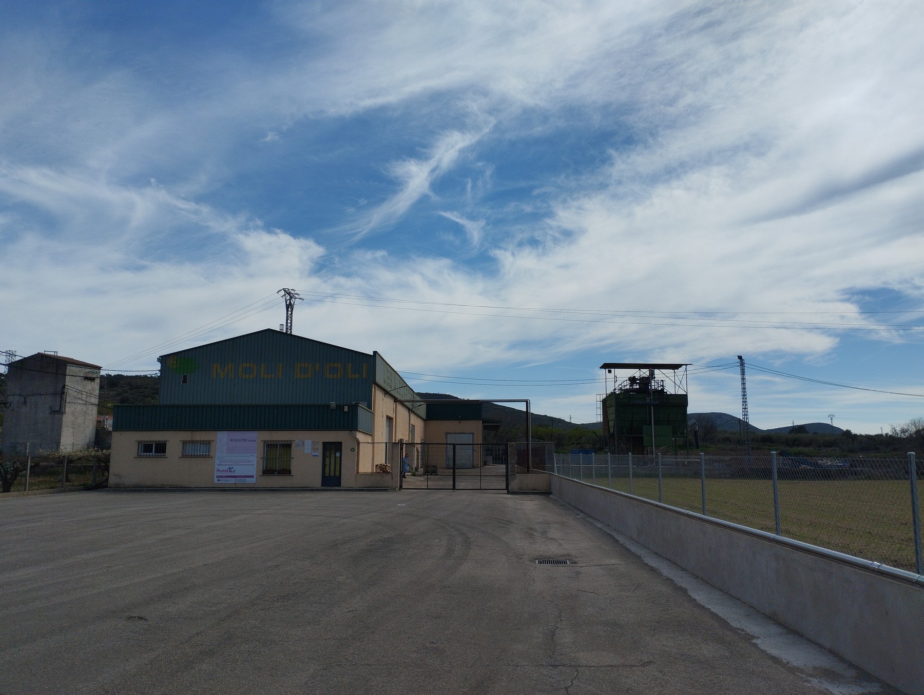 Fachada principal de la almazara Roesan con letrero Molí d oli y montañas al fondo